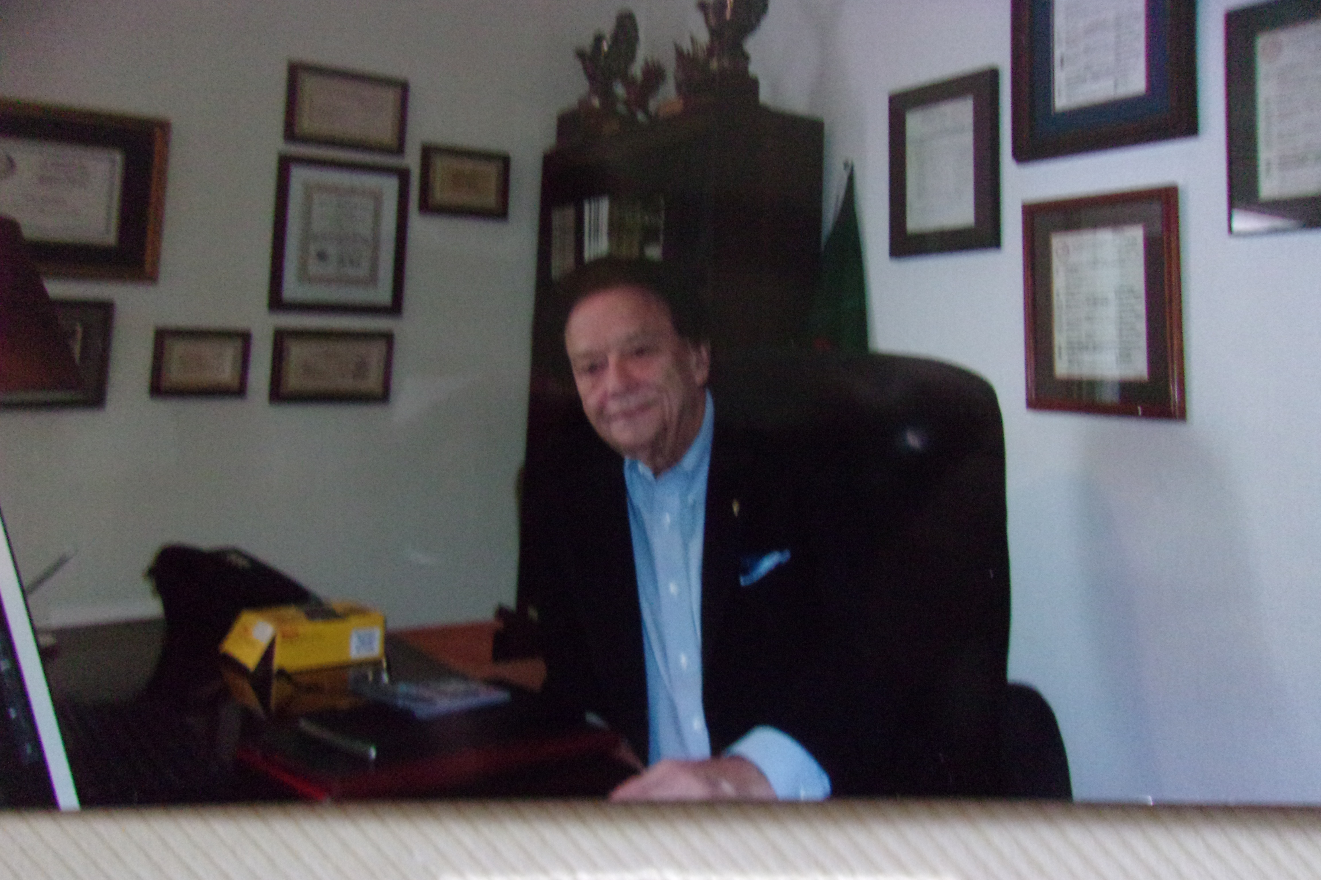 John Michael at his desk surrounded by awards and achievements